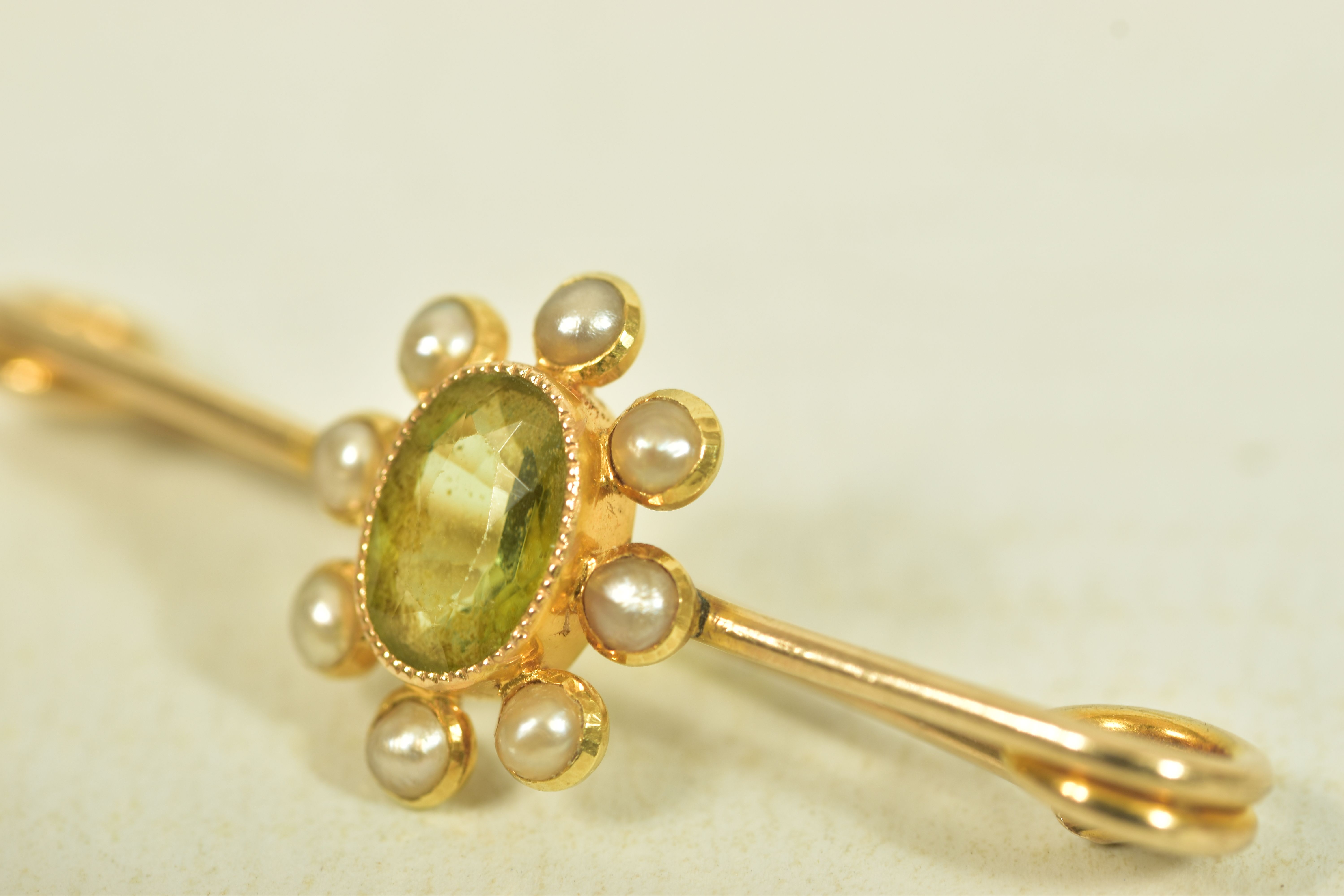 A YELLOW METAL PERIDOT AND SPLIT PEARL BAR BROOCH, the oval collet set peridot, within a split pearl - Image 2 of 3