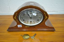 AN EDWARDIAN MAHOGANY AND INLAID MANTLE CLOCK, with a silvered oval dial (winding handle and