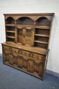 A REPRODUCTION OAK DRESSER, with an arrangement of cupboards and shelves, over a base with four