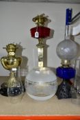 THREE OIL LAMPS, two with glass reservoirs, the tallest measuring approximately 54cm having a square