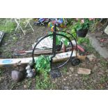 A BLACK PAINTED METAL FRAMED PLANT POT HOLDER in the shape of a penny farthing together with a small