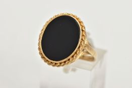 A 9CT GOLD ONYX RING, a large oval onyx slice, inlayed in a yellow gold mount with a rope detail