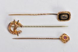 THREE EARLY 20TH CENTURY GOLD STICK PINS, the first a Etruscan style set with circular cut ruby in a