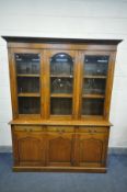 A REPRODUCTION OAK TRIPLE GLAZED DOOR BOOKCASE, with bevelled glass panels, enclosing six shelves,