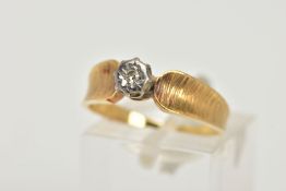 A YELLOW METAL DIAMOND RING, a single round brilliant diamond, set in a white metal illusion