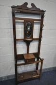 AN EDWARDIAN OAK HALL STAND, with six iron hooks, flanking an oval mirror, width 76cm x depth 26cm x