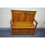 A 20TH CENTURY OAK HALL SETTLE, with open armrests, and a hinged lid storage compartment, labelled