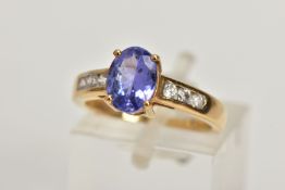 A 9CT GOLD TANZANITE AND COLOURLESS GEM DRESS RING, the oval tanzanite, to the circular colourless