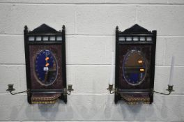 A PAIR OF EARLY 20TH CENTURY EBONISED GIRANDOLES, with an oval mirror, two brass candle holders