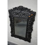 A 19TH CENTURY EBONISED CARVED OAK WALL MIRROR, with lions mask and foliate decoration, and bevelled