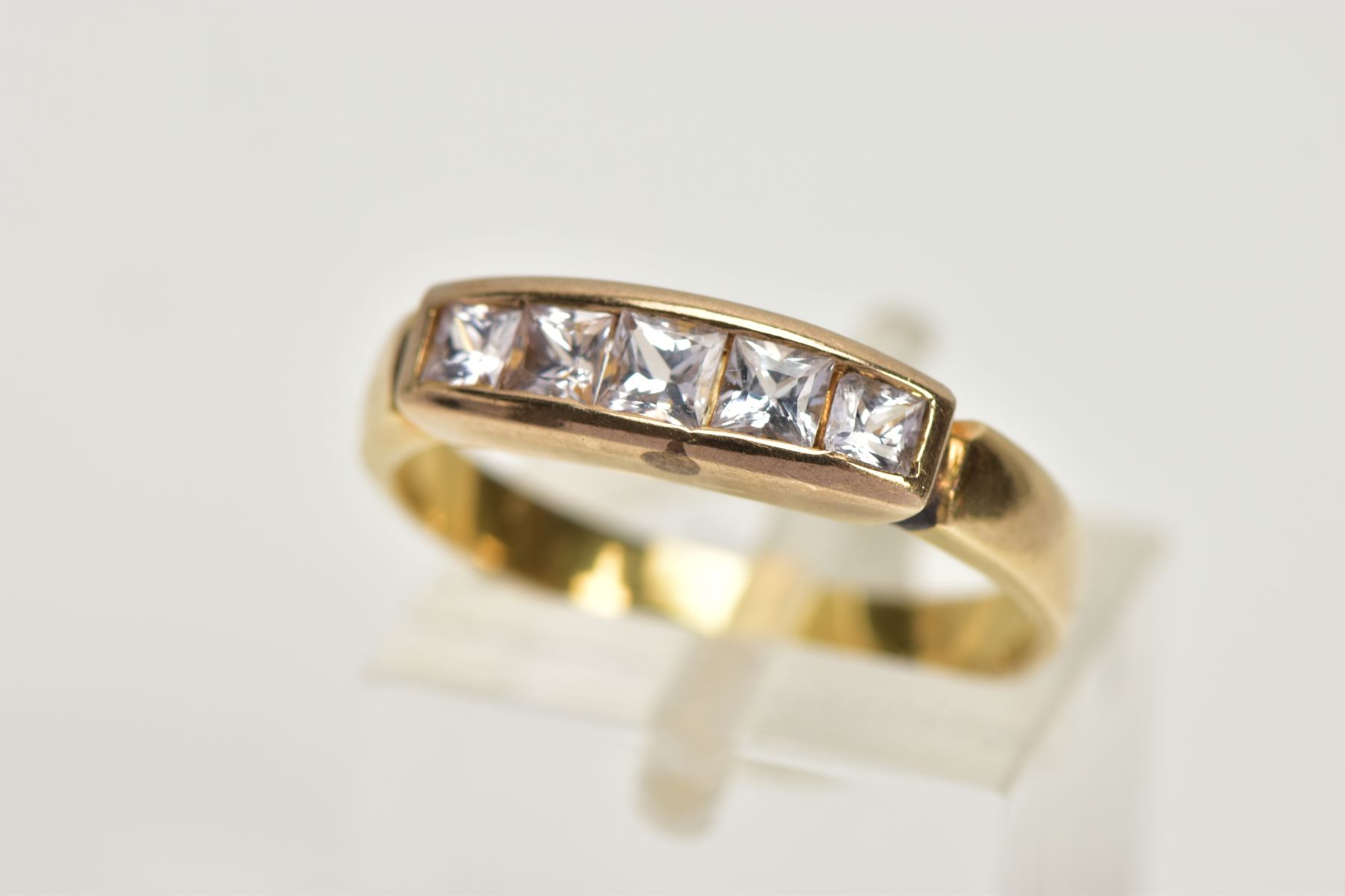 A YELLOW METAL COLOURLESS GEM FIVE STONE RING, designed as five graduated square cut colourless gems