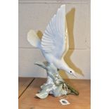 A LLADRO TURTLE DOVE, model no 4550, perched on leaves with wings raised, designed by Fulgencio