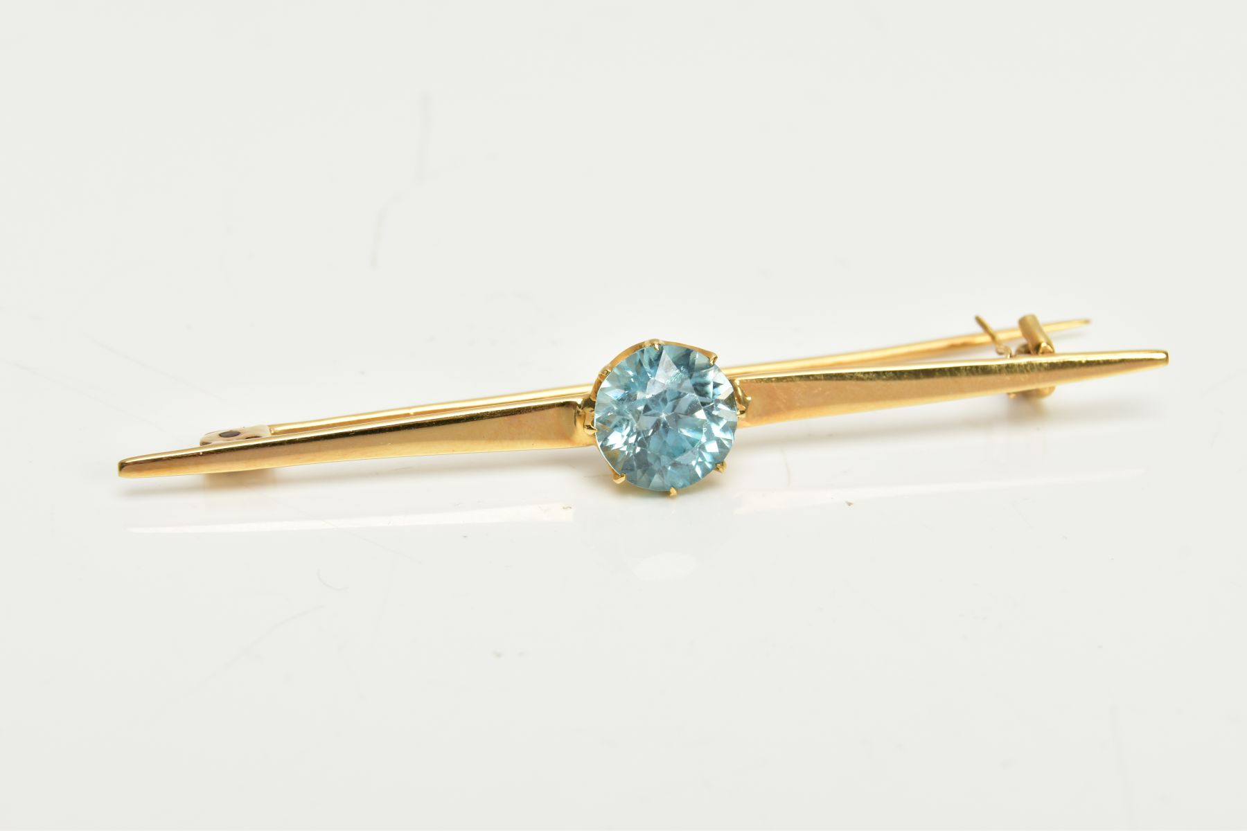 A YELLOW METAL ZIRCON BAR BROOCH, set with a circular blue zircon, measuring approximately 8.5 x 8.