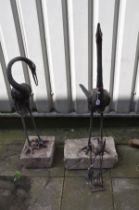A PAIR OF METAL JAPANESE CRANE FIGURES, both figures with their necks in different positions, on a