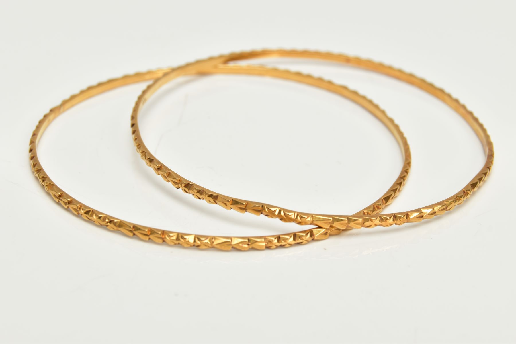 TWO YELLOW METAL BANGLES, each with embossed detail, approximate inner diameter 61mm, stamped 22c,