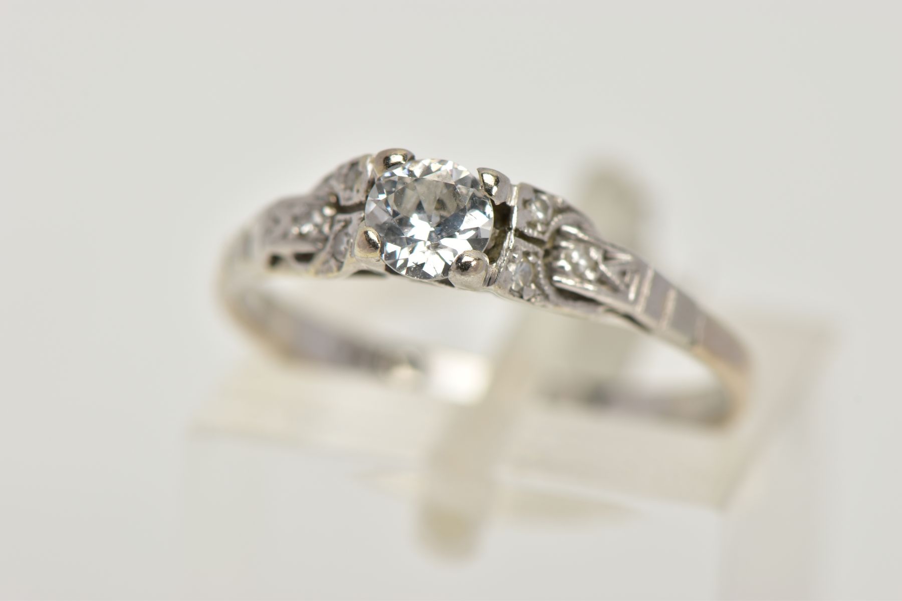 A WHITE METAL DIAMOND RING, centring on a four claw set, round brilliant cut diamond, estimated