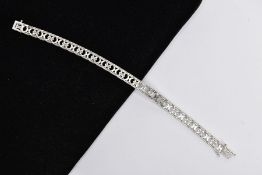 A WHITE METAL DIAMOND OPENWORK BRACELET, with a trilogy of brilliant-cut diamonds each interspaced