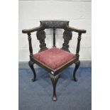 A LATE 19TH/EARLY 20TH CENTURY CARVED OAK CORNER CHAIR with a drop in seat pad