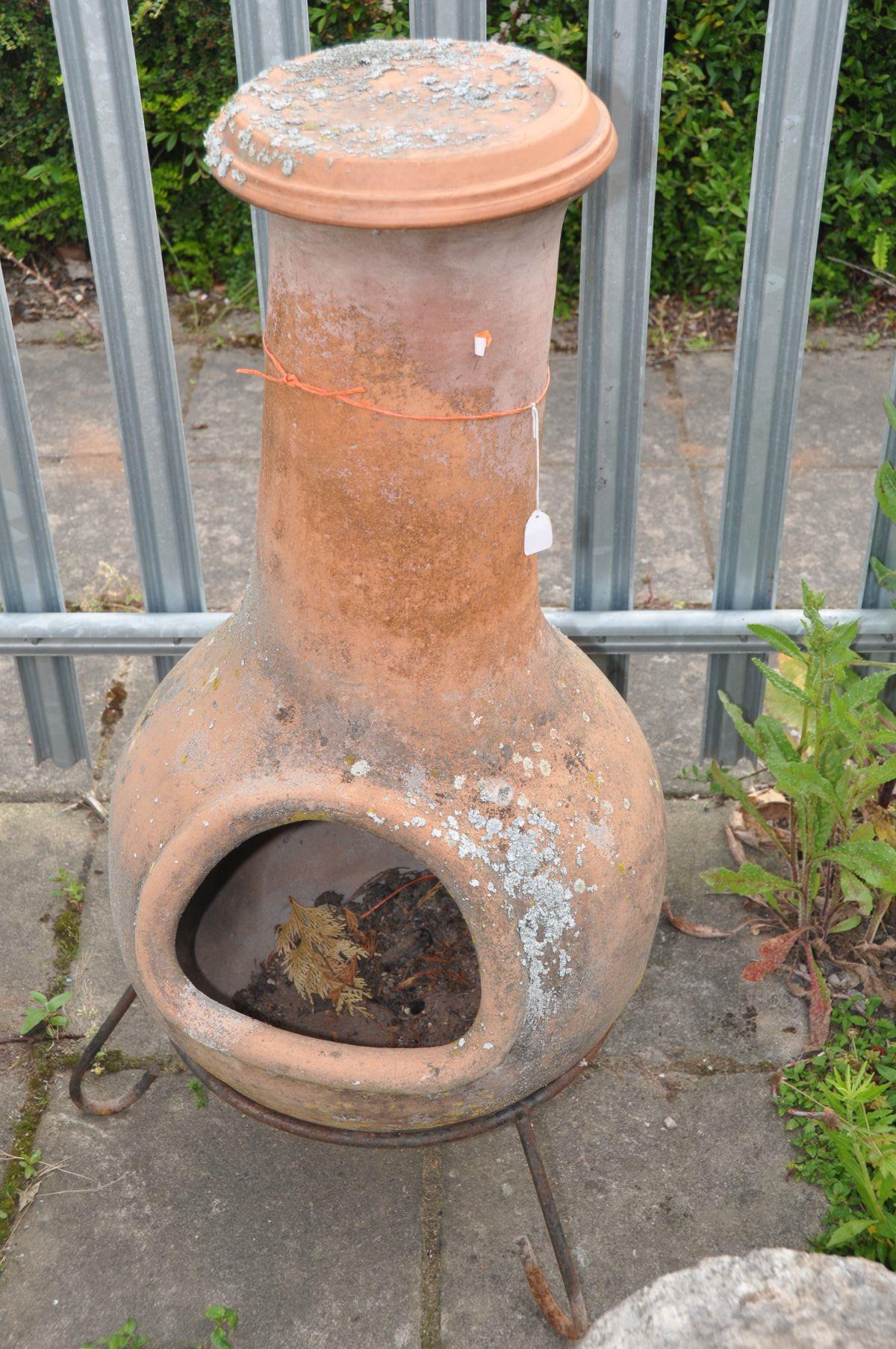 A LARGE TERRACOTTA CHIMINEA, with a later lid, on a wrought iron stand, overall height 103cm