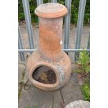 A LARGE TERRACOTTA CHIMINEA, with a later lid, on a wrought iron stand, overall height 103cm