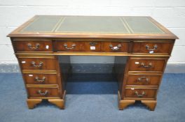 A YEWWOOD PEDESTAL DESK, the top with a green leather writing surface, and an arrangement of nine