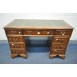 A YEWWOOD PEDESTAL DESK, the top with a green leather writing surface, and an arrangement of nine