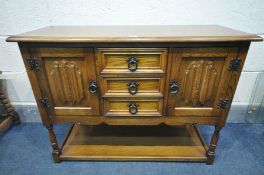 AN OAK LINENFOLD TWO DOOR CABINET, with three central drawers, on turned legs united by an