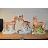 A PAIR OF VICTORIAN STAFFORDSHIRE POTTERY FIGURES OF GREYHOUNDS CARRYING RABBITS, modelled as