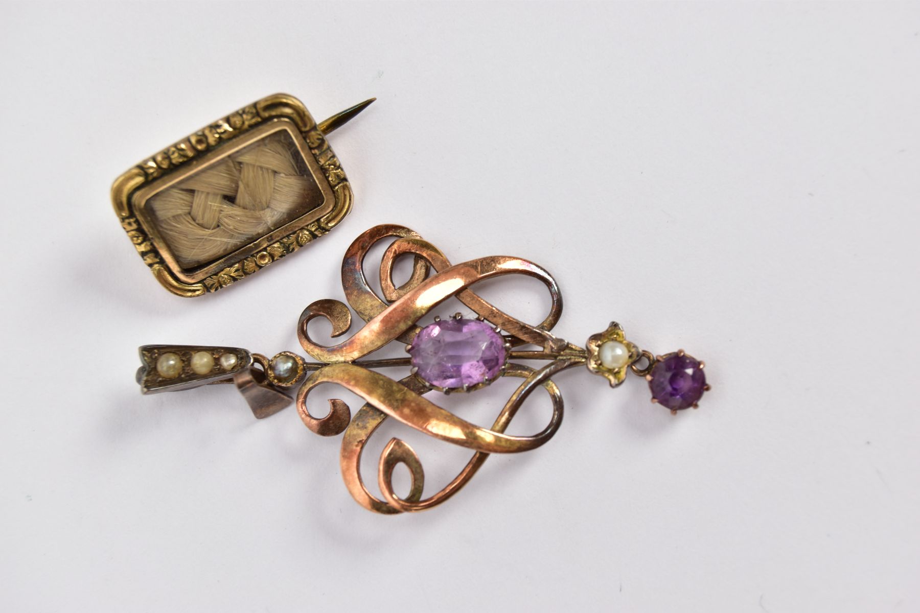 AN AMETHYST AND SPLIT PEARL YELLOW METAL PENDANT AND A WOVEN HAIR MEMORIAL YELLOW METAL BROOCH,