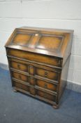 AN OAK BUREAU, with a fitted interior, and three exterior drawers, width 77cm x depth 47cm x