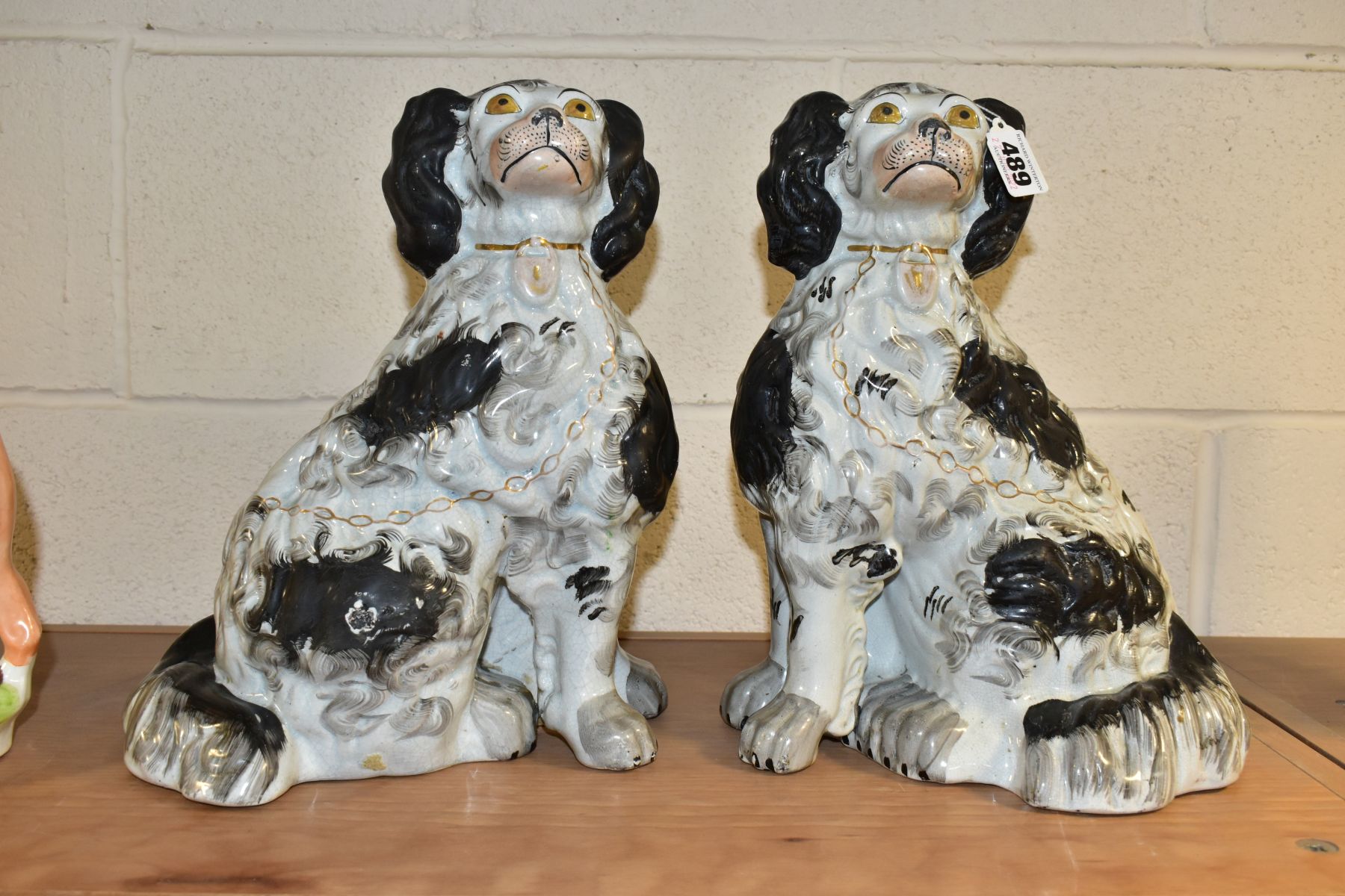 A PAIR OF VICTORIAN STAFFORDSHIRE POTTERY CURLY COATED BLACK AND WHITE SEATED SPANIELS, one