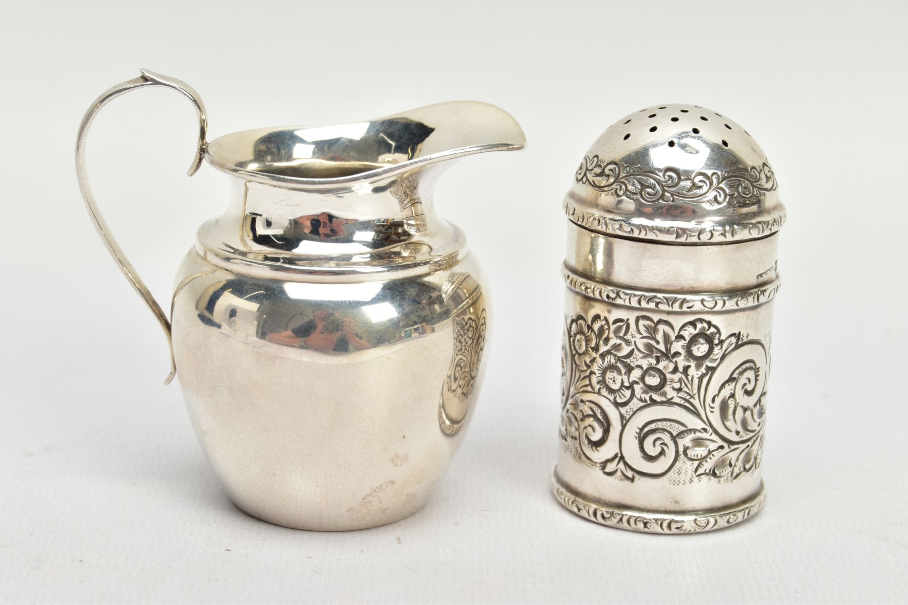 A LATE VICTORIAN PEPPER POT AND AN EDWARDIAN SILVER JUG, the first a late Victorian engraved