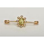 A YELLOW METAL PERIDOT AND SPLIT PEARL BAR BROOCH, the oval collet set peridot, within a split pearl