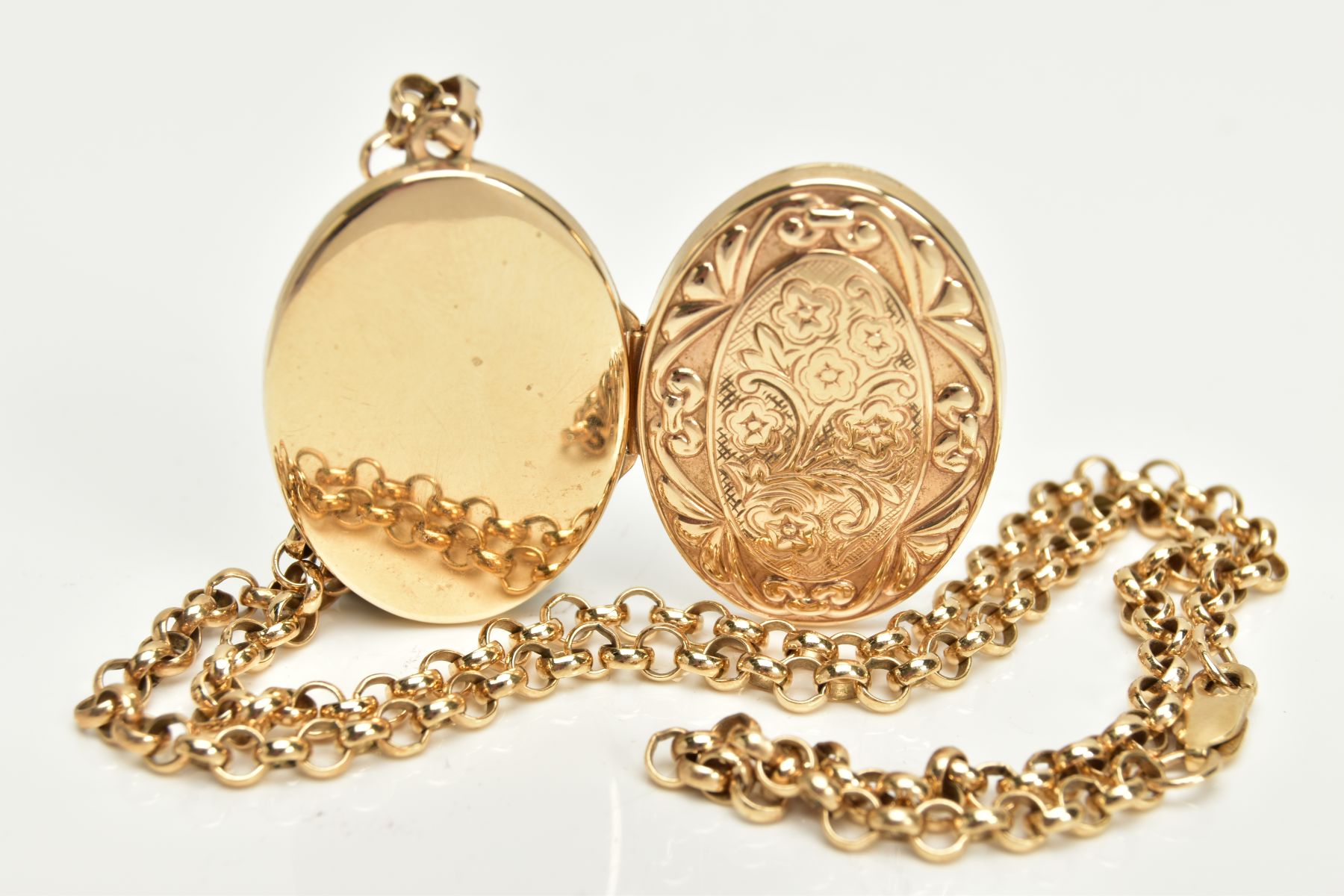 A 9CT GOLD LOCKET AND CHAIN, oval floral and scroll detailed locket, opens to reveal two photo