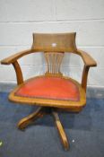 AN EARLY 2OTH CENTURY OAK SWIVEL OFFICE CHAIR, with red leather upholstered seat, on four legs,