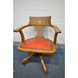 AN EARLY 2OTH CENTURY OAK SWIVEL OFFICE CHAIR, with red leather upholstered seat, on four legs,