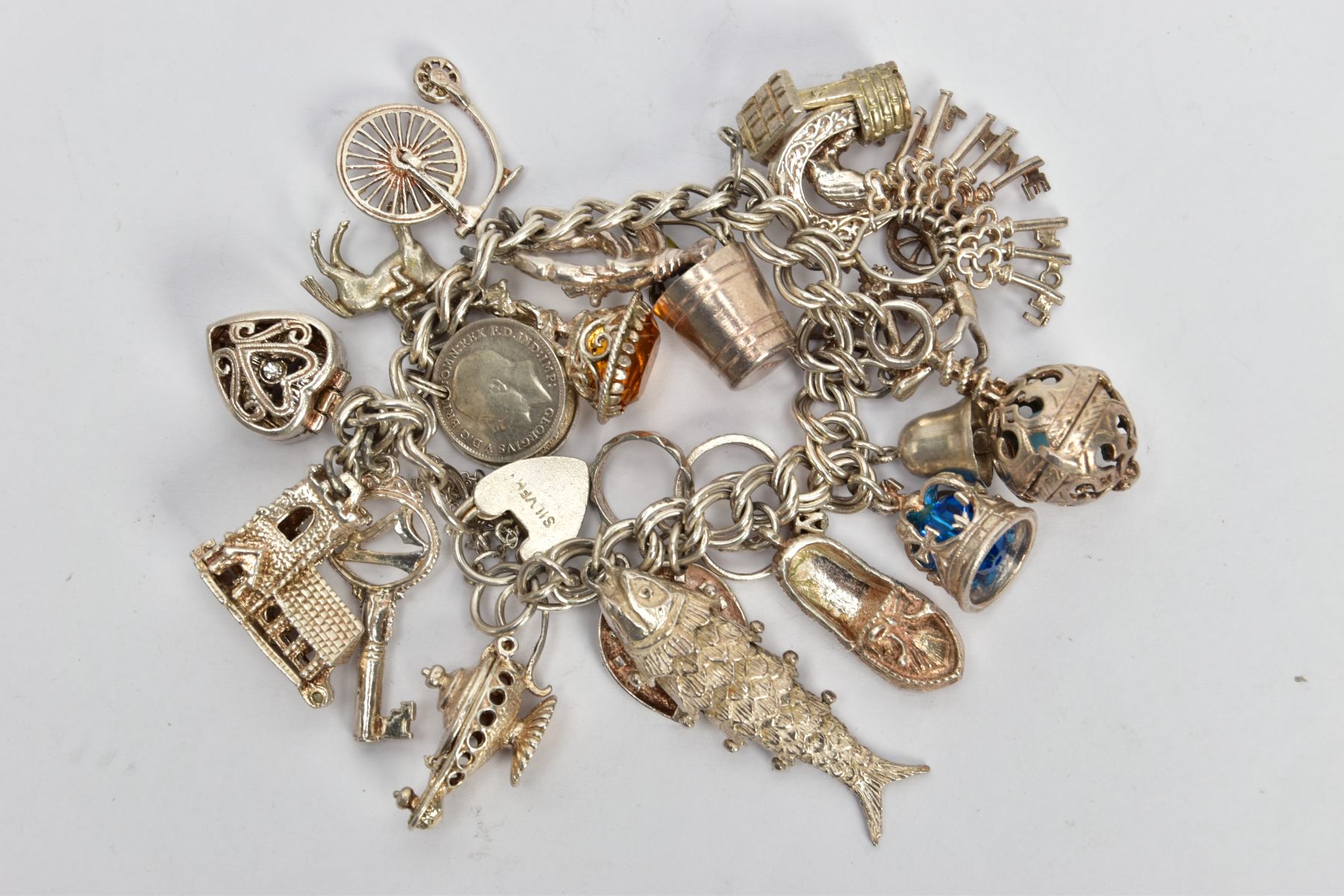 A WHITE METAL CHARM BRACELET, comprising approximately twenty plus various charms to include a fish,