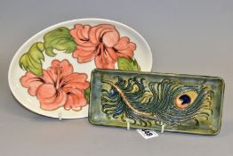 A MOORCROFT PEACOCK FEATHERS RECTANGULAR TRAY AND A MOORCROFT CORAL HIBISCUS OVAL TRAY, the former