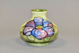 A MOORCROFT POTTERY SQUAT BALUSTER VASE DECORATED WITH PUPLE CLEMATIS ON A SHADED GREEN GROUND,