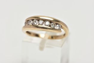 A YELLOW METAL DIAMOND RING, seven round brilliant cut diamonds, channel set in a bypass yellow