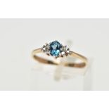 A 9CT YELLOW GOLD TOPAZ AND DIAMOND DRESS RING, set with a principal oval cut blue topaz, flanked to