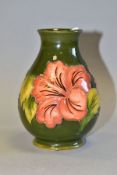 A MOORCROFT POTTERY BALUSTER VASE DECORATED WITH CORAL HIBISCUS, on a green ground, impressed