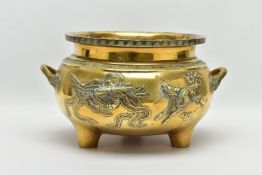 A CHINESE BRASS TWIN HANDLED TRIPOD CENSER OF CIRCULAR FORM, cast in relief with four dragons, the