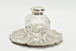 A VICTORIAN SILVER AND GLASS INKWELL ON STAND, of wavy circular outline, foliate engraved decoration