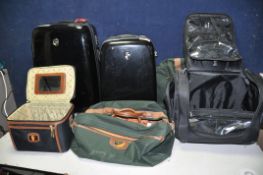 A COLLECTION OF LUGGAGE to include two hard gloss black hard shell suitcases, two Antler holdalls,