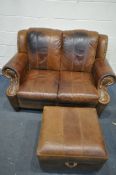 A BROWN LEATHER TWO SEATER SOFA, and an ottoman footstool (condition - dark stains to back and seat)