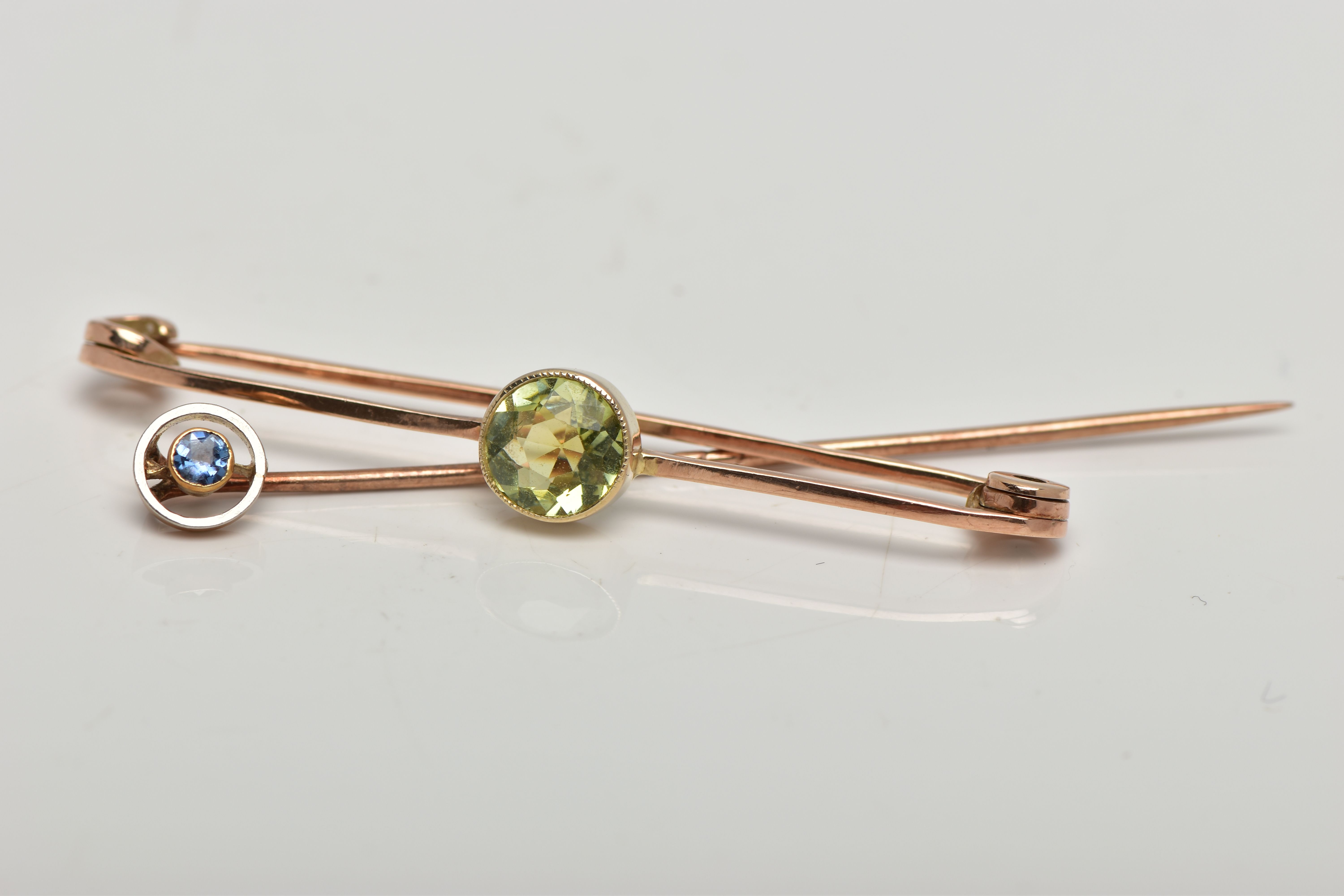 A PERIDOT BAR BROOCH AND A SAPPHIRE STICK PIN, the circular shape peridot collet set measuring