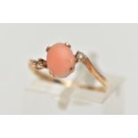 A YELLOW METAL CORAL AND CUBIC ZIRCONIA RING, the oval coral cabochon, with asymmetric colourless