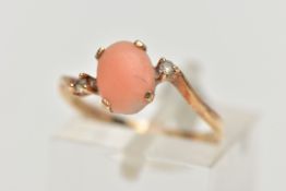 A YELLOW METAL CORAL AND CUBIC ZIRCONIA RING, the oval coral cabochon, with asymmetric colourless