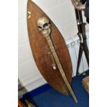 A WOODEN SHIELD AND STAFF, the staff has a carved skull on top, length 110cm, the shield is carved